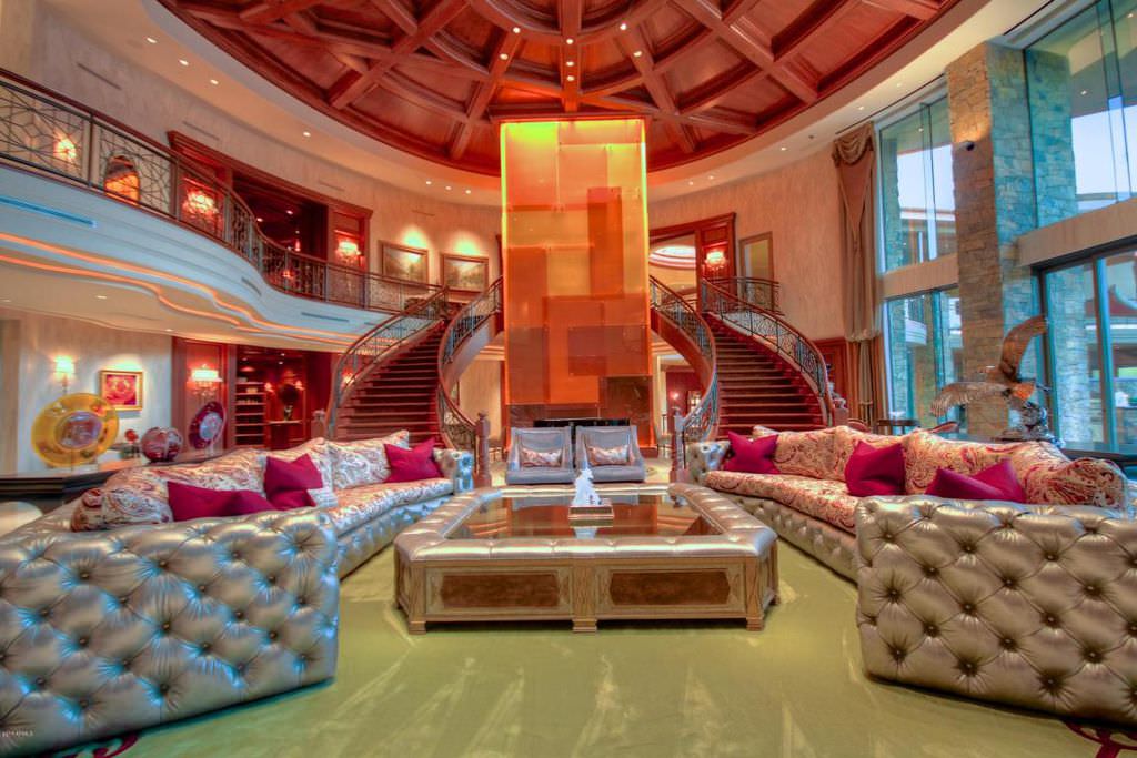 نشیمن بزرگ خانه دوبلکس لوکسی که با مبل های طوسی چسترفیلد، کوسن های سرخابی و میز جلو مبلی طوسی دکور شده است